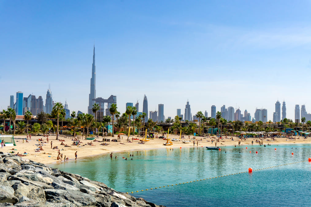 Beach in Dubai with people and skyscrapers in the background