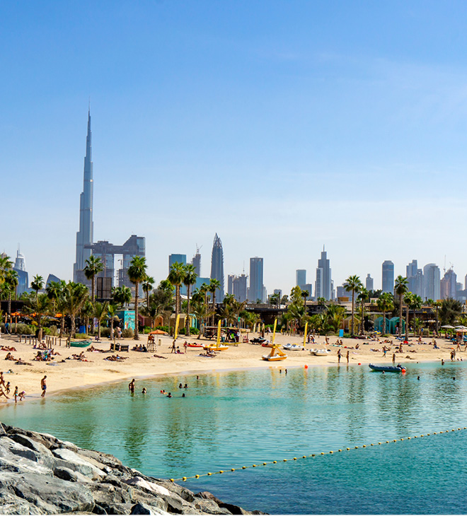 Beach in Dubai with people and skyscrapers in the background